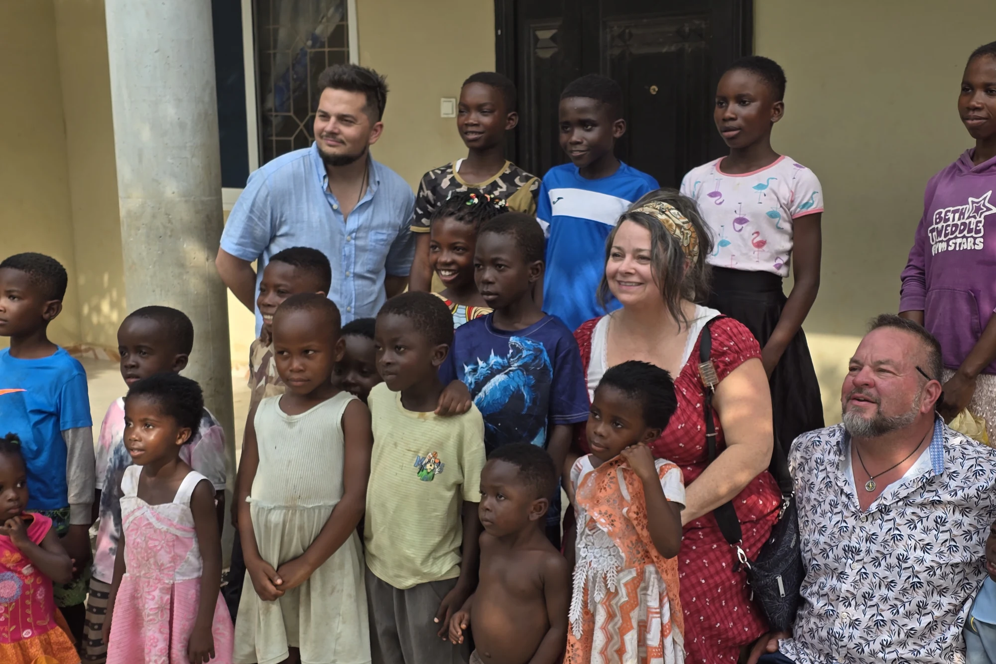 Pastor Tave, Heather and TJ with the children on the steps of Kai'Ros House